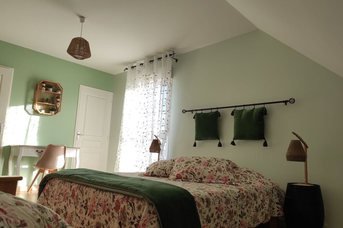 Un dormitorio con cama, escritorio, silla, lámpara colgante y ventana con cortinas.