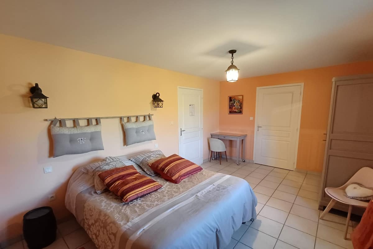 A bedroom with a bed, bedside tables, a desk, and a chair.