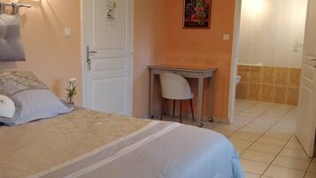 Une chambre avec un lit, un bureau et une chaise. Il y a une porte avec une pancarte et un tableau au mur.