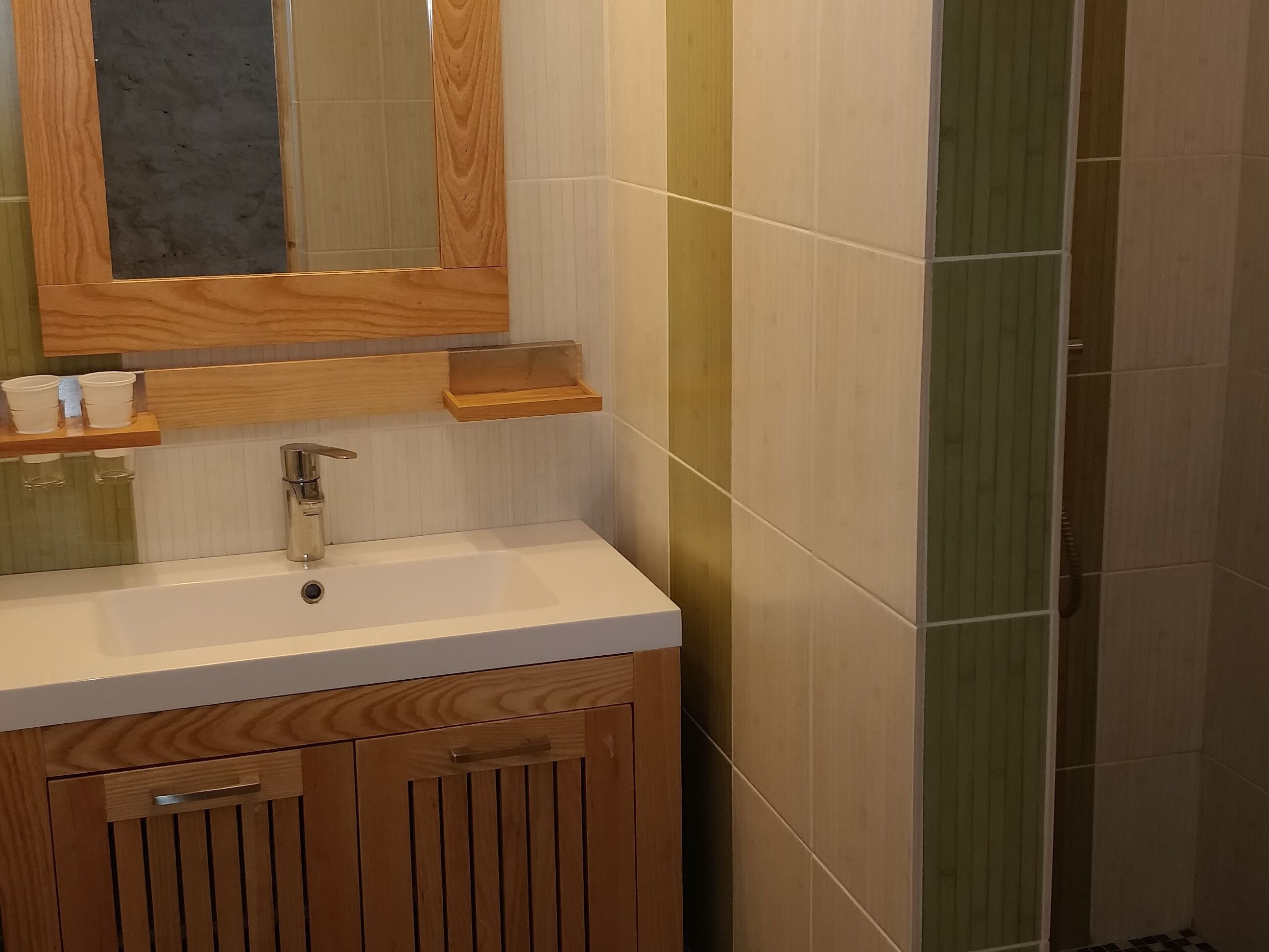 Een badkamer met een houten wastafelmeubel, een spiegel en een witte wasbak.