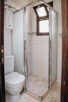 Un baño con ducha, inodoro y ventana sobre la ducha.