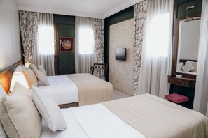 A hotel room with two beds, a TV, a mirror, a desk, and a shower.
