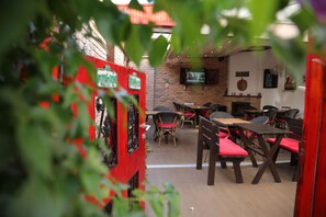 An indoor dining area with brick walls, wooden tables, and wicker chairs.