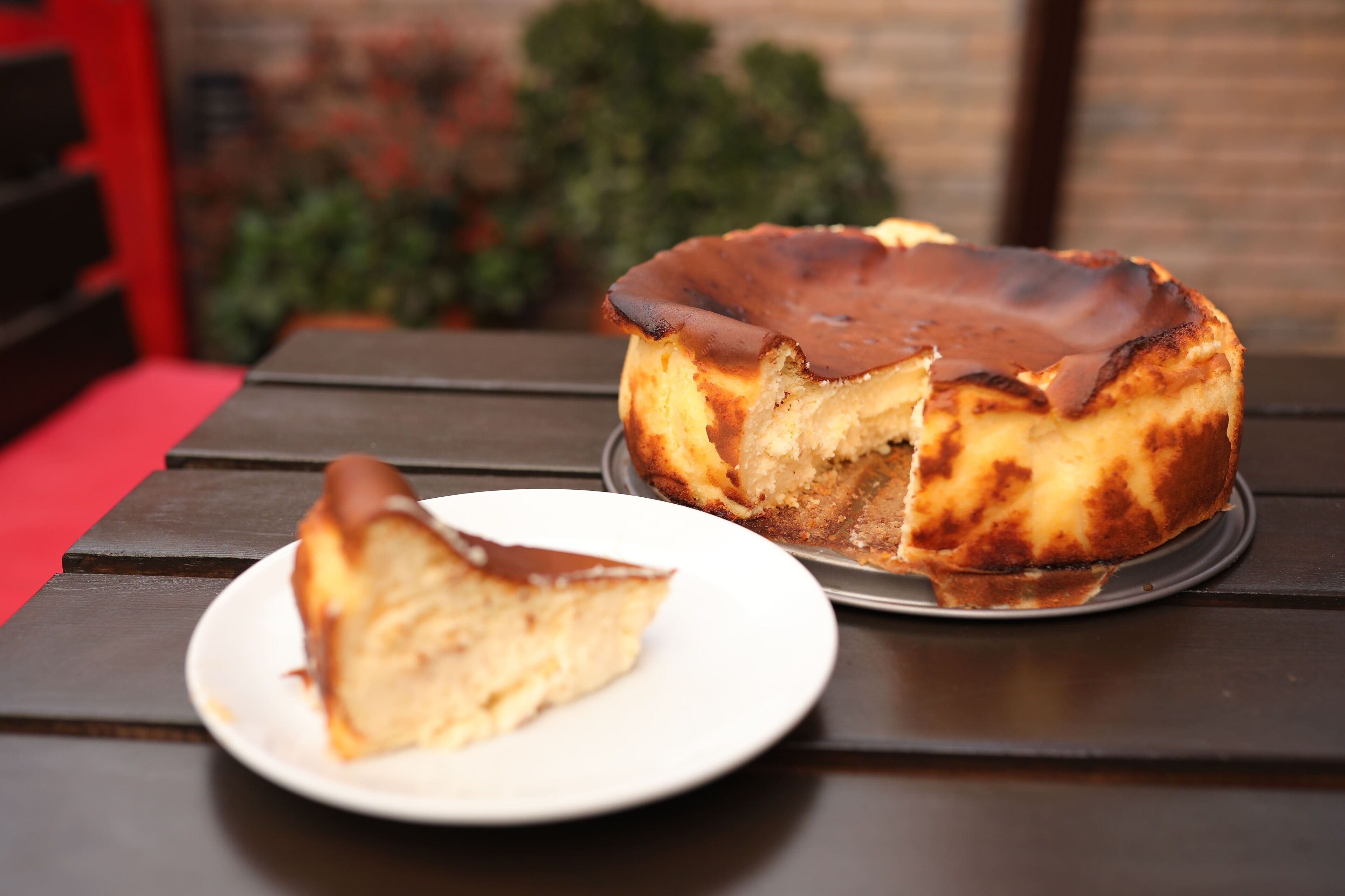 Un pastel de queso en un plato con una porción cortada, sobre una mesa.