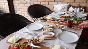 A table set for a meal with various dishes, including olives, cheese, and vegetables, and a pitcher of tea. - Mandalin Pansiyon (Seferihisar)