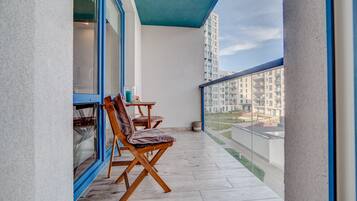 A balcony with two wooden chairs and a small table, overlooking a residential area.