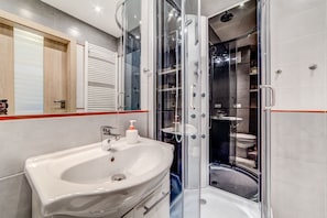 A modern bathroom with a glass-enclosed shower, a white sink, and a mirror with a wooden frame. - Rint - Centrum Kaczorowskiego (Bialystok)