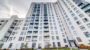 A modern high-rise building with multiple balconies and a central entrance. - Rint - Centrum Kaczorowskiego (Bialystok)