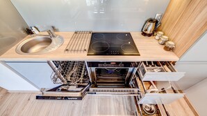 A modern kitchen with a built-in dishwasher, oven, and a wooden countertop. - Rint - Centrum Kaczorowskiego (Bialystok)