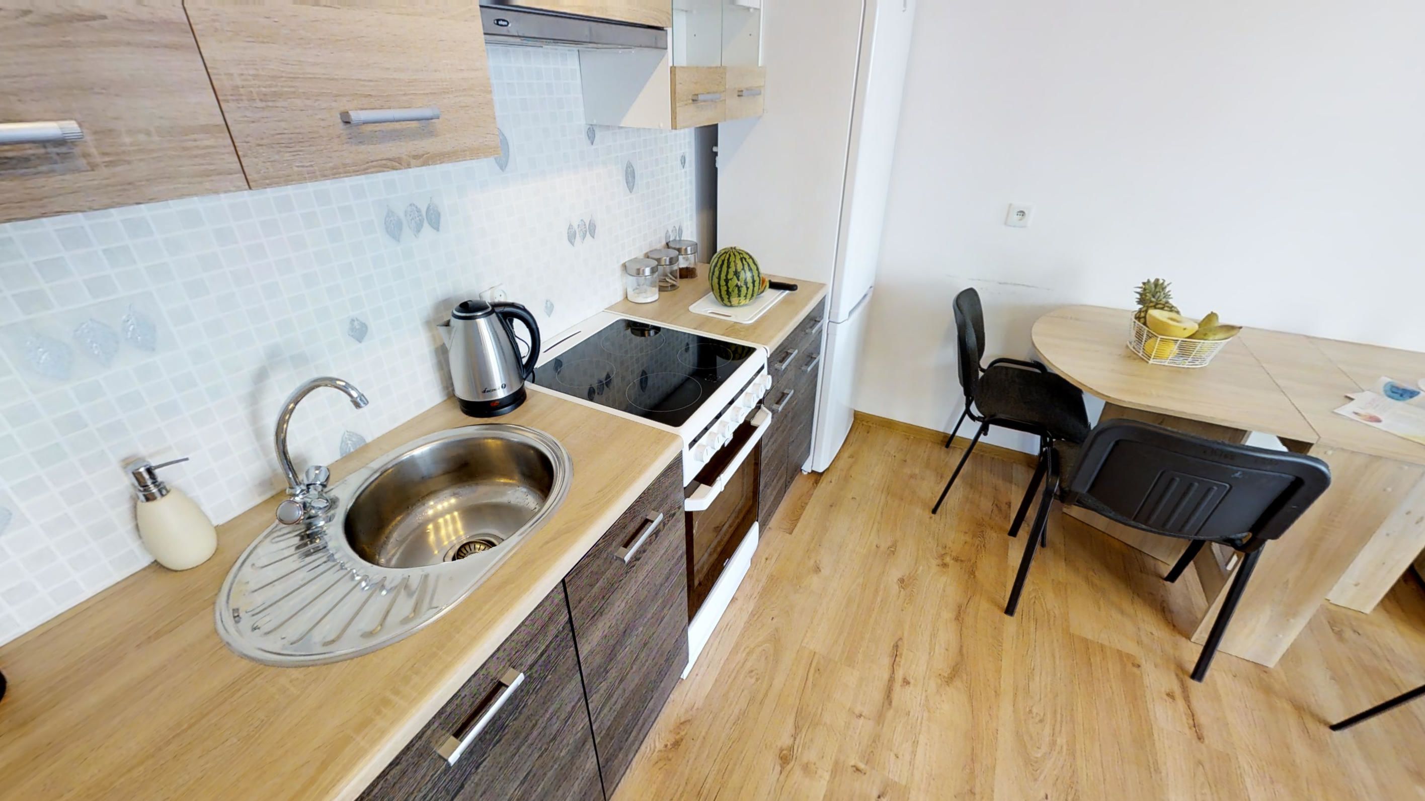 Una cocina compacta con fregadero, cocina y un pequeño comedor con mesa y sillas.