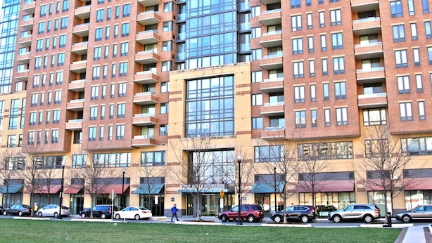 A multi-story building with a brick facade and large windows. - Weichert Suites at The Bartlett (Arlington)