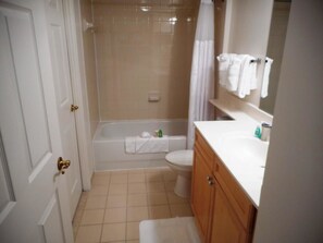 A bathroom with a bathtub, toilet, and vanity.