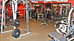 A gym with various exercise equipment, mirrors, and a red wall. - Weichert Suites at Thomas Circle (Washington)