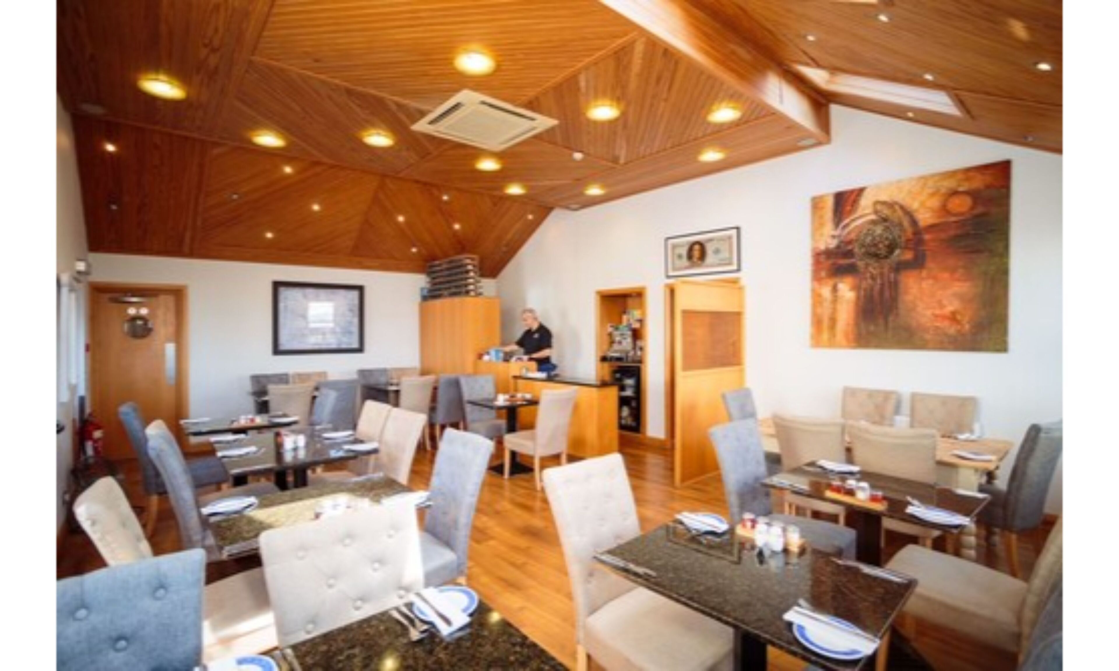 Un grand espace dédié à la salle à manger, avec un plafond en bois et de nombreuses tables et chaises.