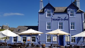 Een blauw gebouw genaamd "The Waterfront" met terras en parasols.