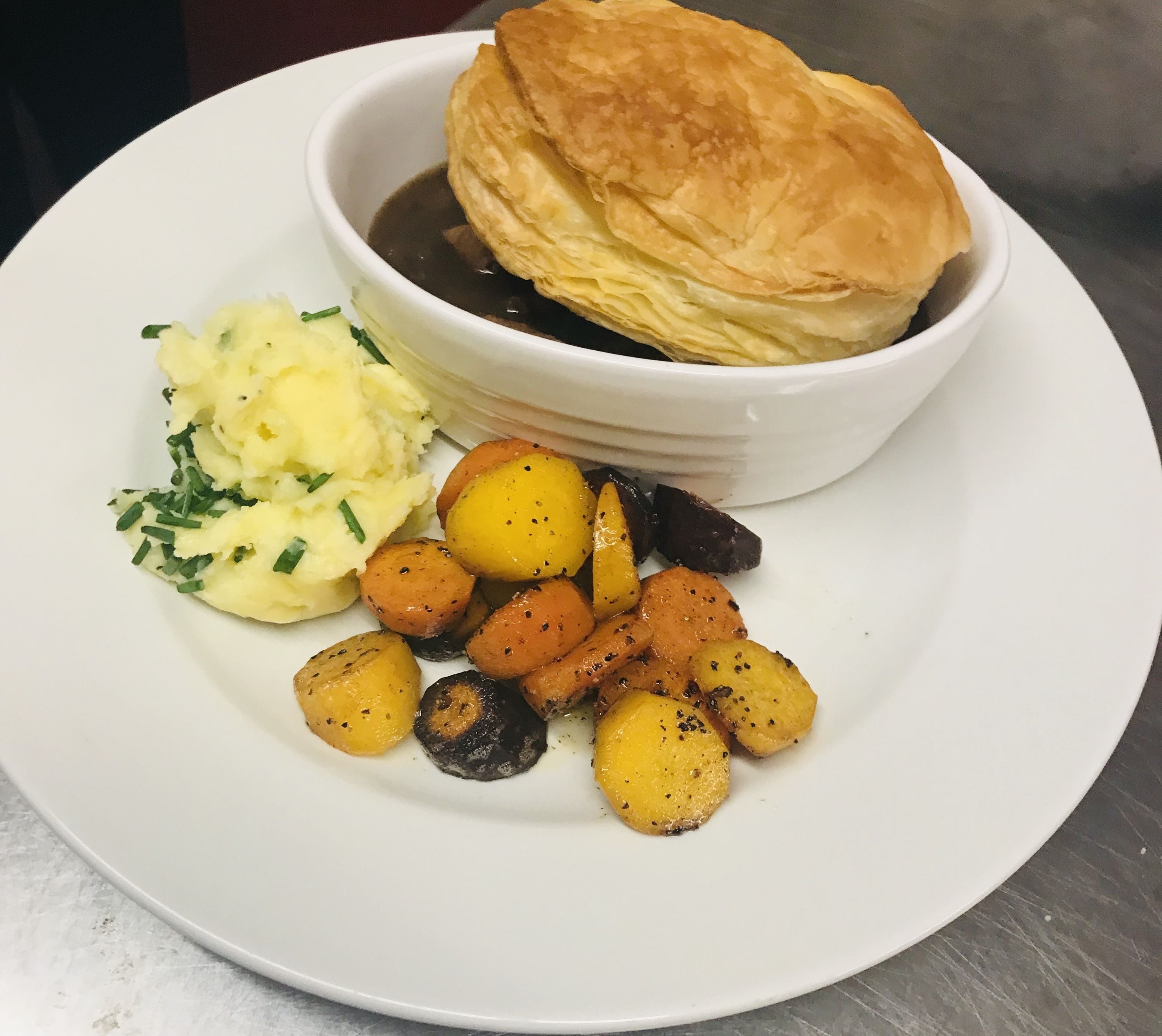 A plate with a pastry, mashed potatoes, and roasted potatoes.