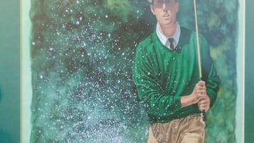 A painting of a golfer in a green sweater and beige pants, holding a golf club.