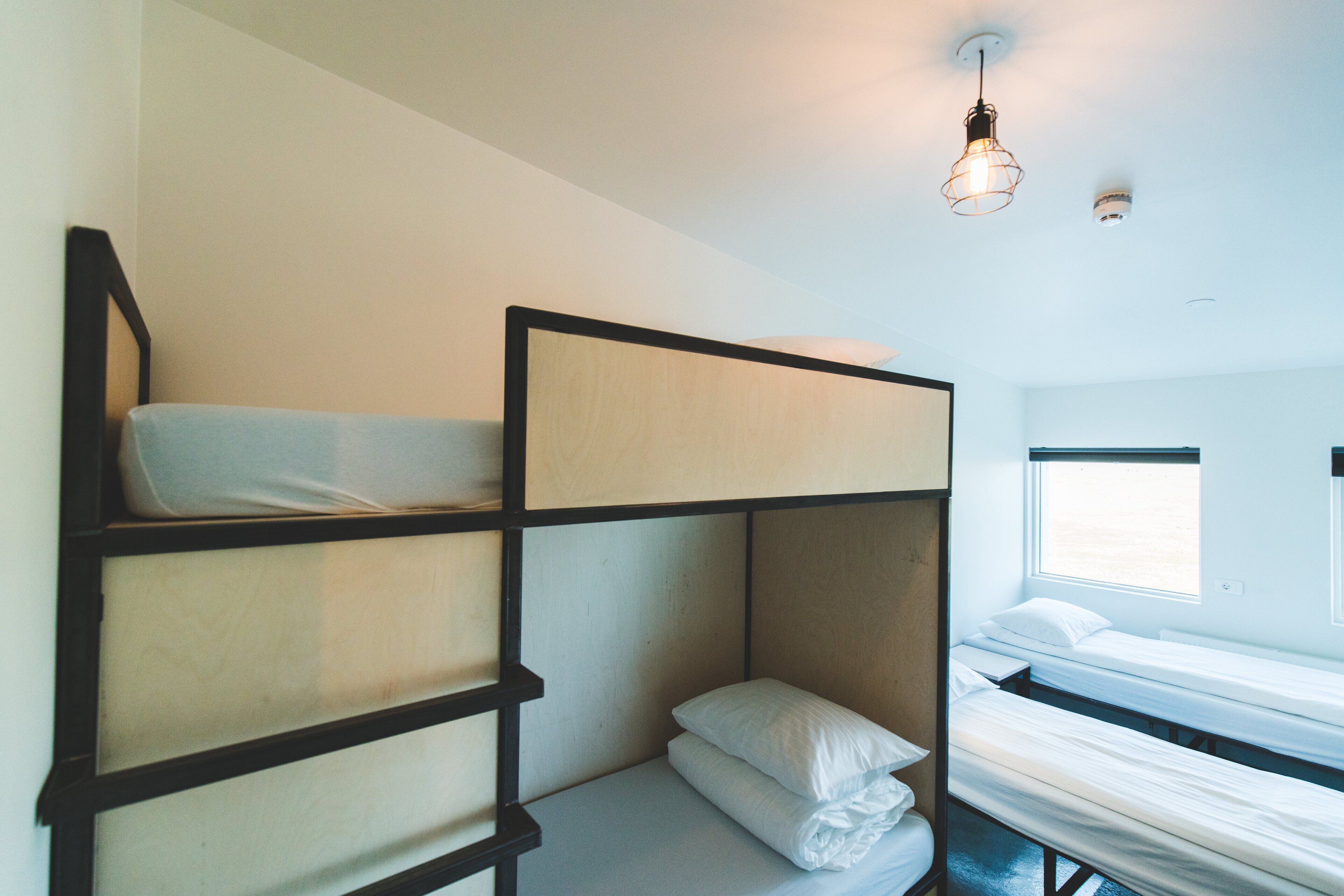 A bunk bed room with a window and a hanging light fixture.