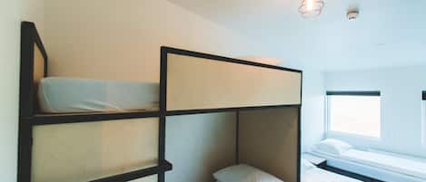 A bunk bed room with a window and a hanging light fixture.