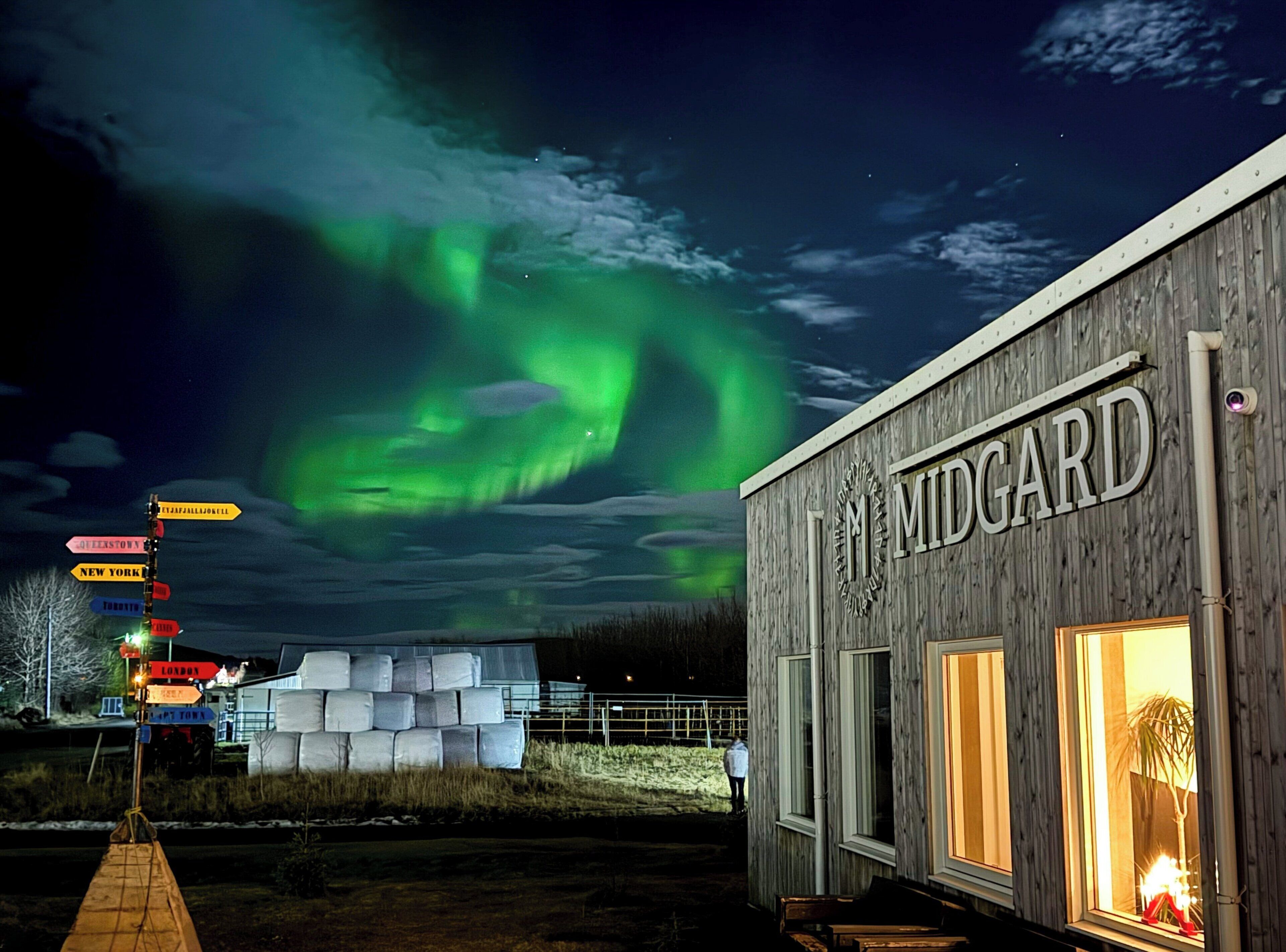 A building named MIDGARD with a wooden exterior and a signboard.
