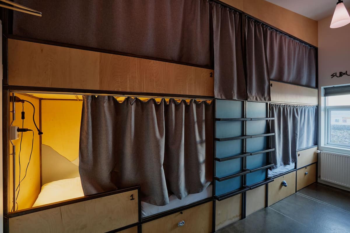 A bunk bed room with curtains, a window, and a radiator.