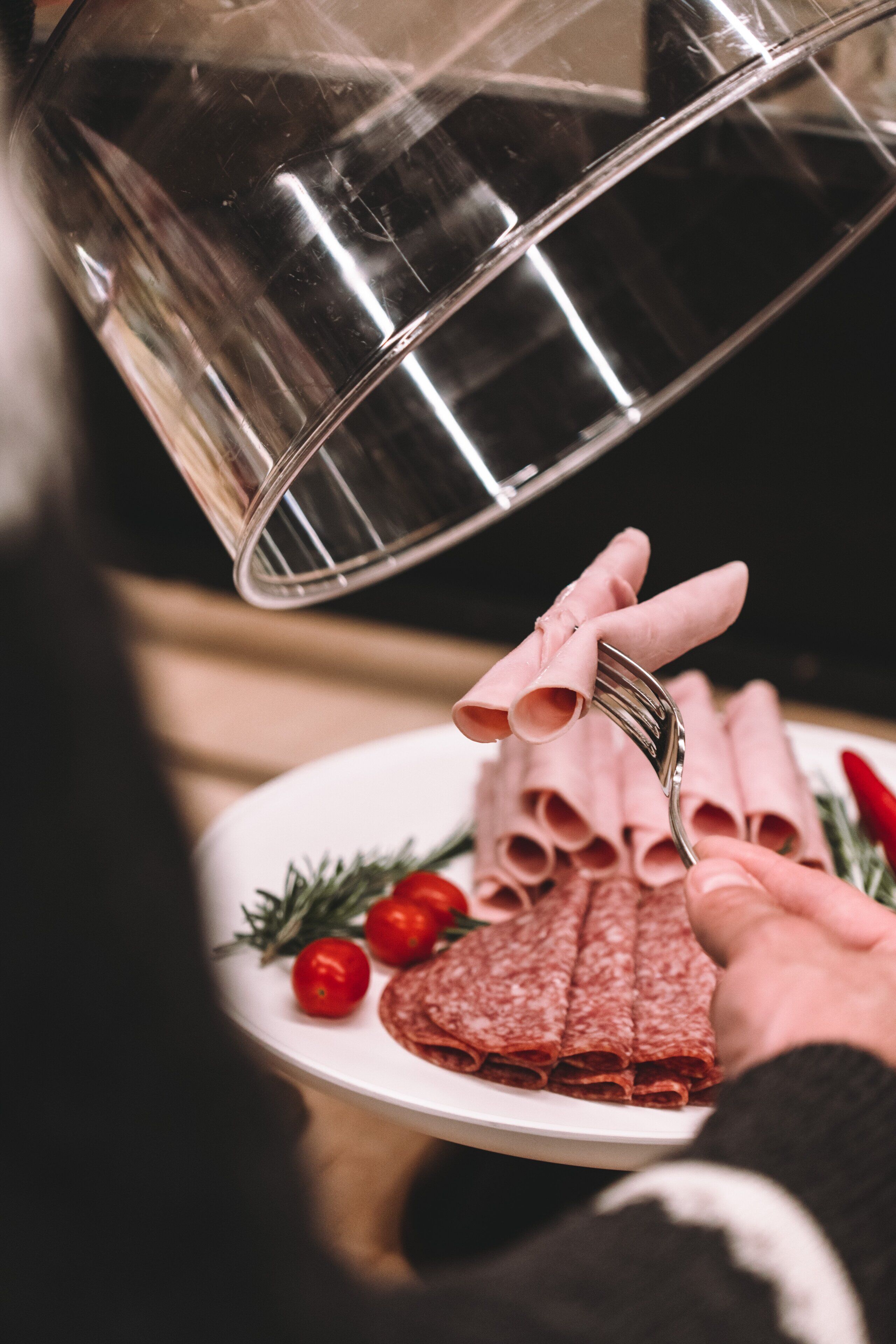 A plate of sliced salami and cherry tomatoes on a white plate.
