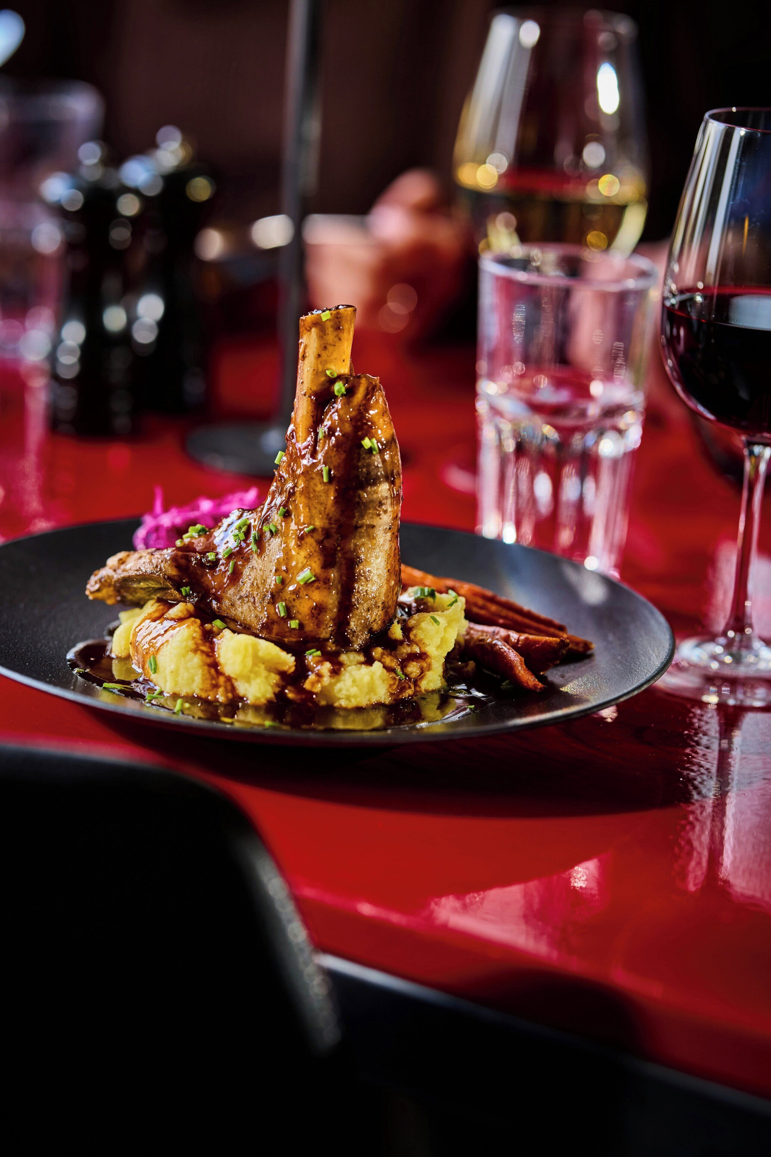 A dining table with a plate of food, glasses, and a bottle.