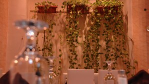 A restaurant interior with hanging plants, a bar area, and a dining setup with tables and chairs.