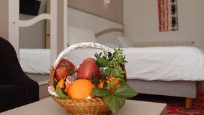 A room with a bed, a wall-mounted TV, and a fruit basket on a table.