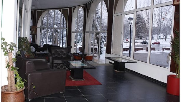 A spacious lobby with large windows, a seating area, and a potted plant.