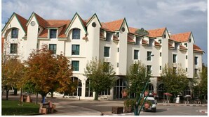 A multi-story hotel with a symmetrical facade, large windows, and a red-tiled roof.