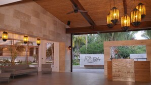 A spacious lobby with a modern design, featuring a ceiling fan, wooden slatted walls, and a reception desk. - Azura Beach Resort - All Inclusive - Adults Only (Sámara)