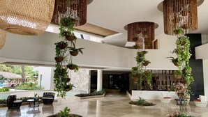 A spacious lobby with a modern design, featuring hanging planters, a pool area, and seating arrangements. - Azura Beach Resort - All Inclusive - Adults Only (Sámara)