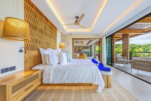 Une chambre moderne avec un grand lit, un ventilateur de plafond et une vue sur un paysage luxuriant.
