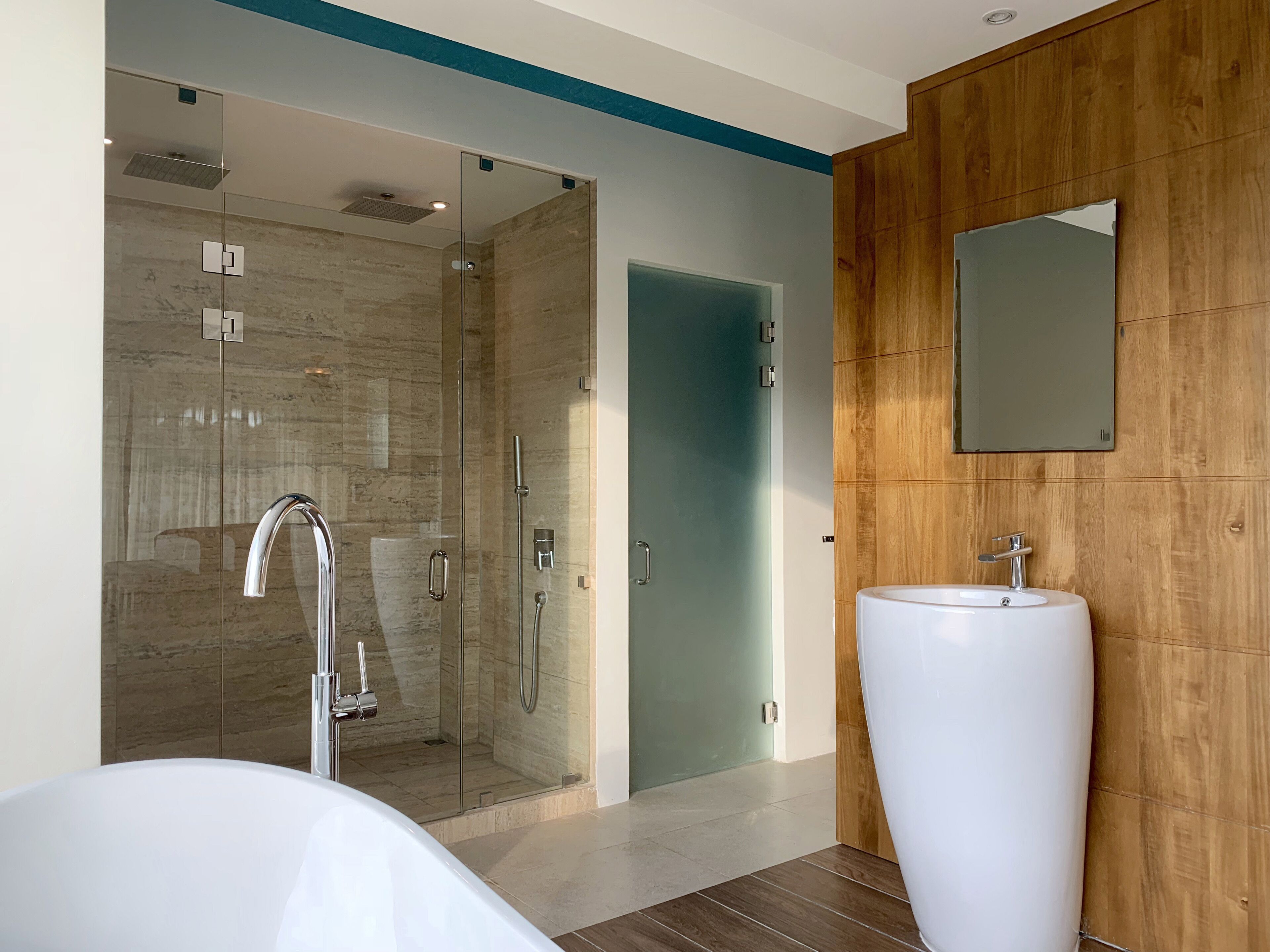 A modern bathroom with a glass-enclosed shower, a white sink, and a wooden panel wall.