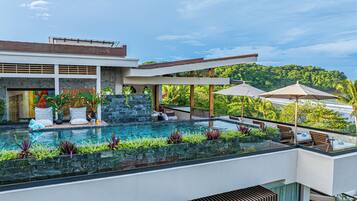Una piscina infinita en la azotea con vistas a un paisaje verde exuberante y un edificio moderno.