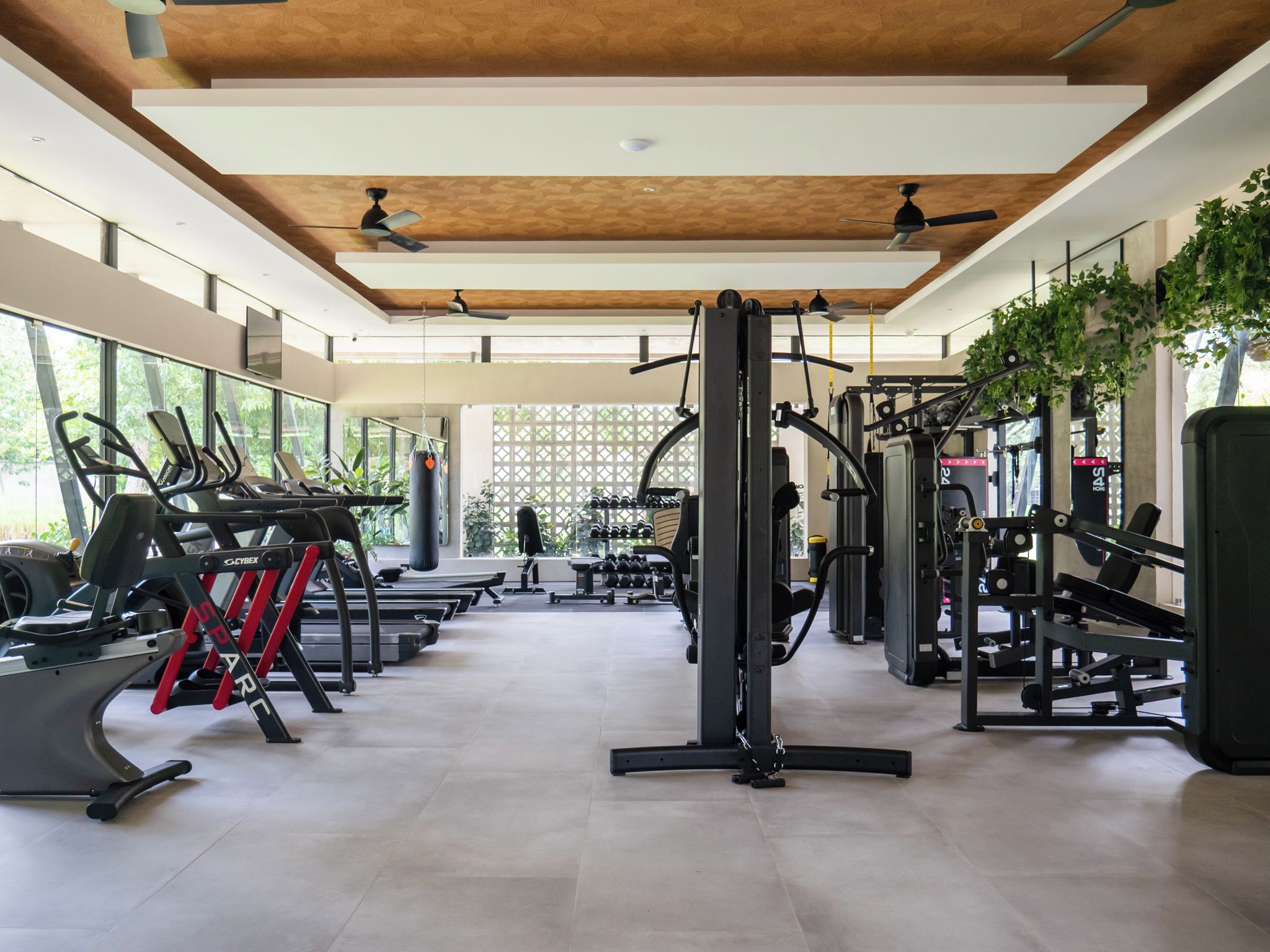 Un gimnasio moderno con cintas de correr, máquinas de pesas y un ventilador de techo.