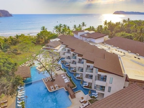 A resort with a swimming pool, multiple buildings, and a view of the ocean. - Azura Beach Resort - All Inclusive - Adults Only (Sámara)