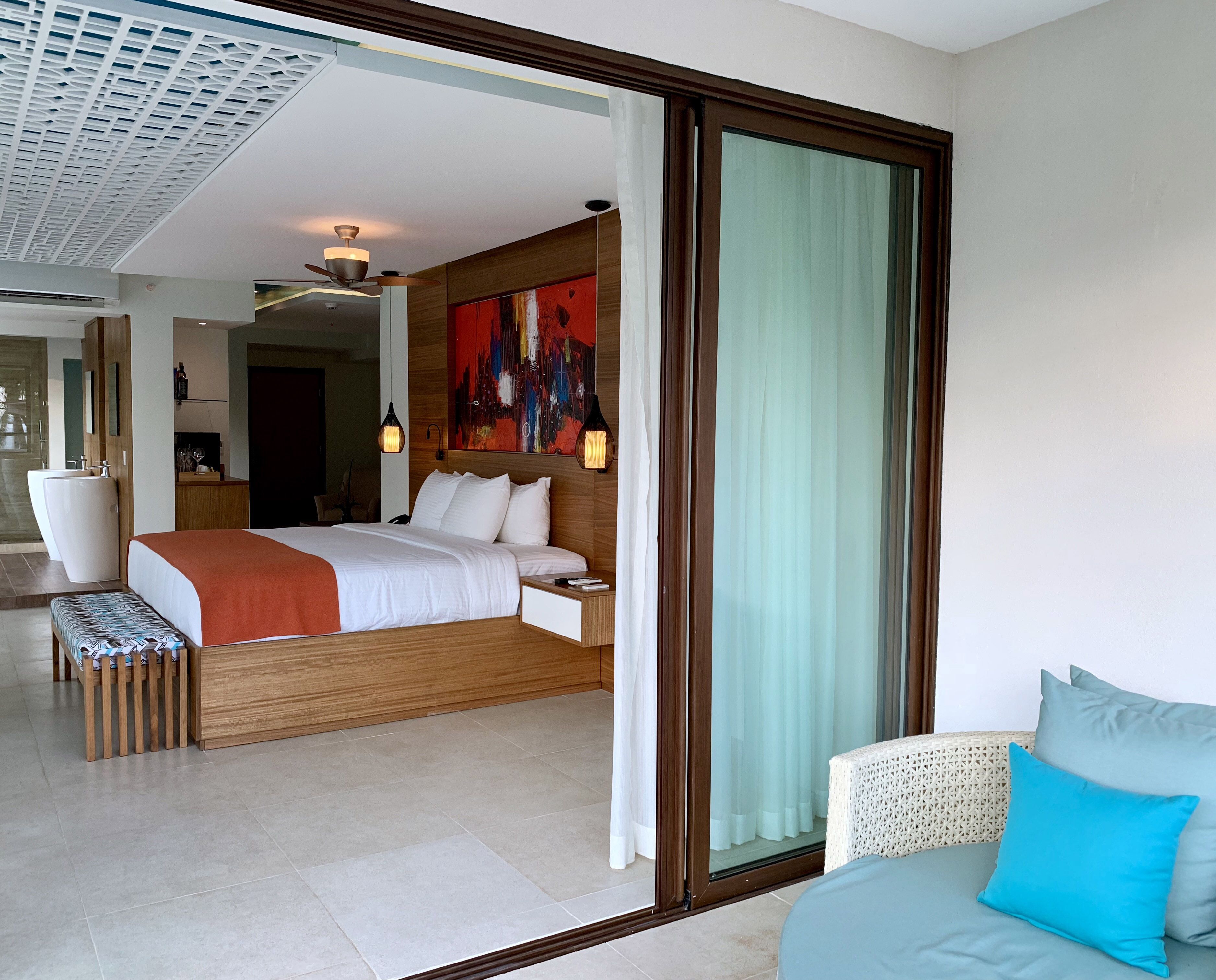 Una habitación de hotel moderna con una cama grande, una mesita de noche y vistas a través de un ventanal corredero.