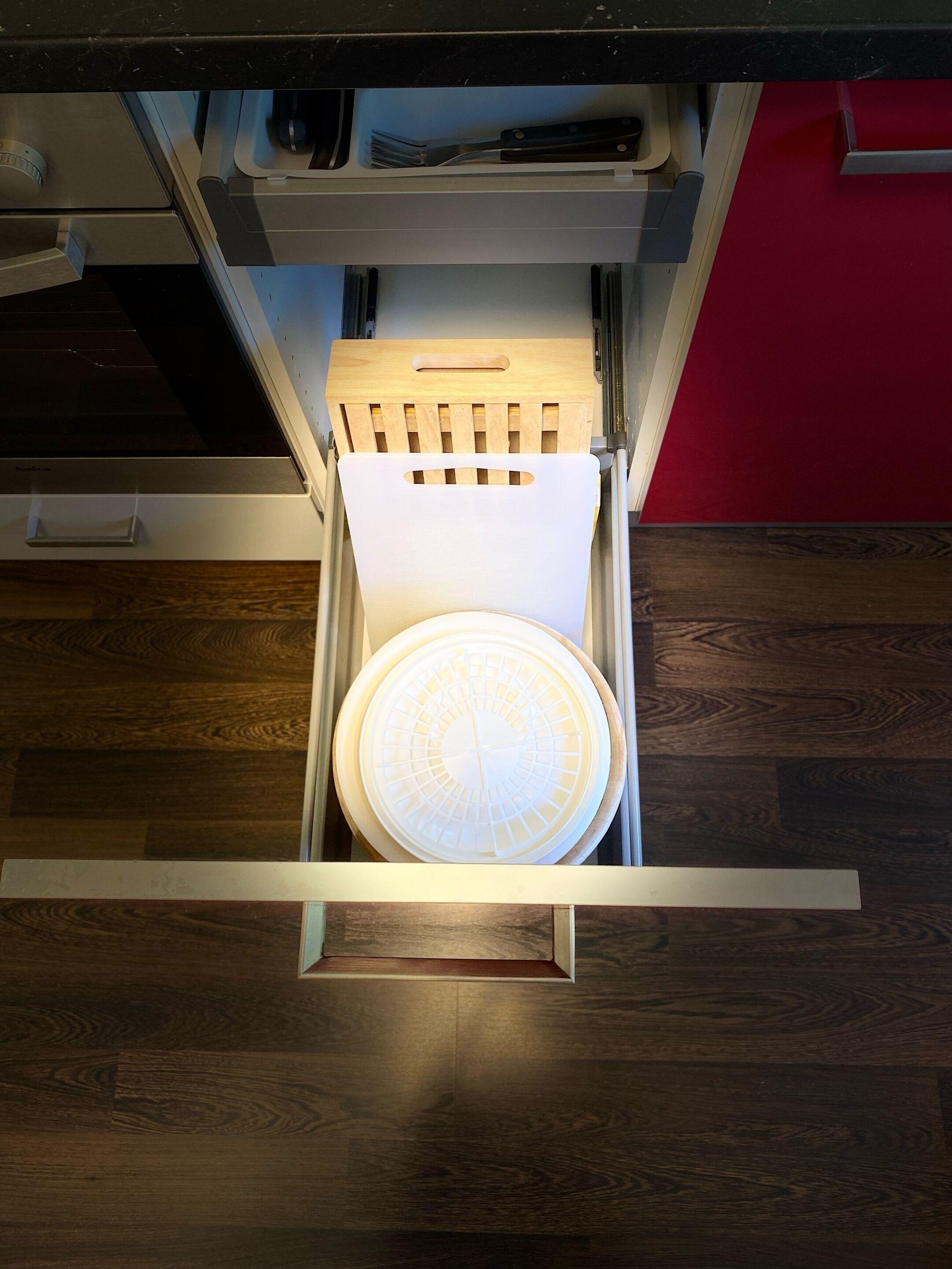 A drawer with a white circular object, a wooden handle, and a metal frame.