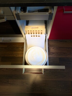 A drawer with a white circular object, a wooden handle, and a metal frame. - Ferienwohnung Hella (Kippenheim)