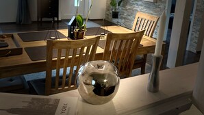 A dining area with a wooden table, chairs, a vase with flowers, and a decorative glass object.