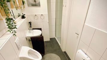 Ein kleines Badezimmer mit Toilette, Waschbecken und Dusche.