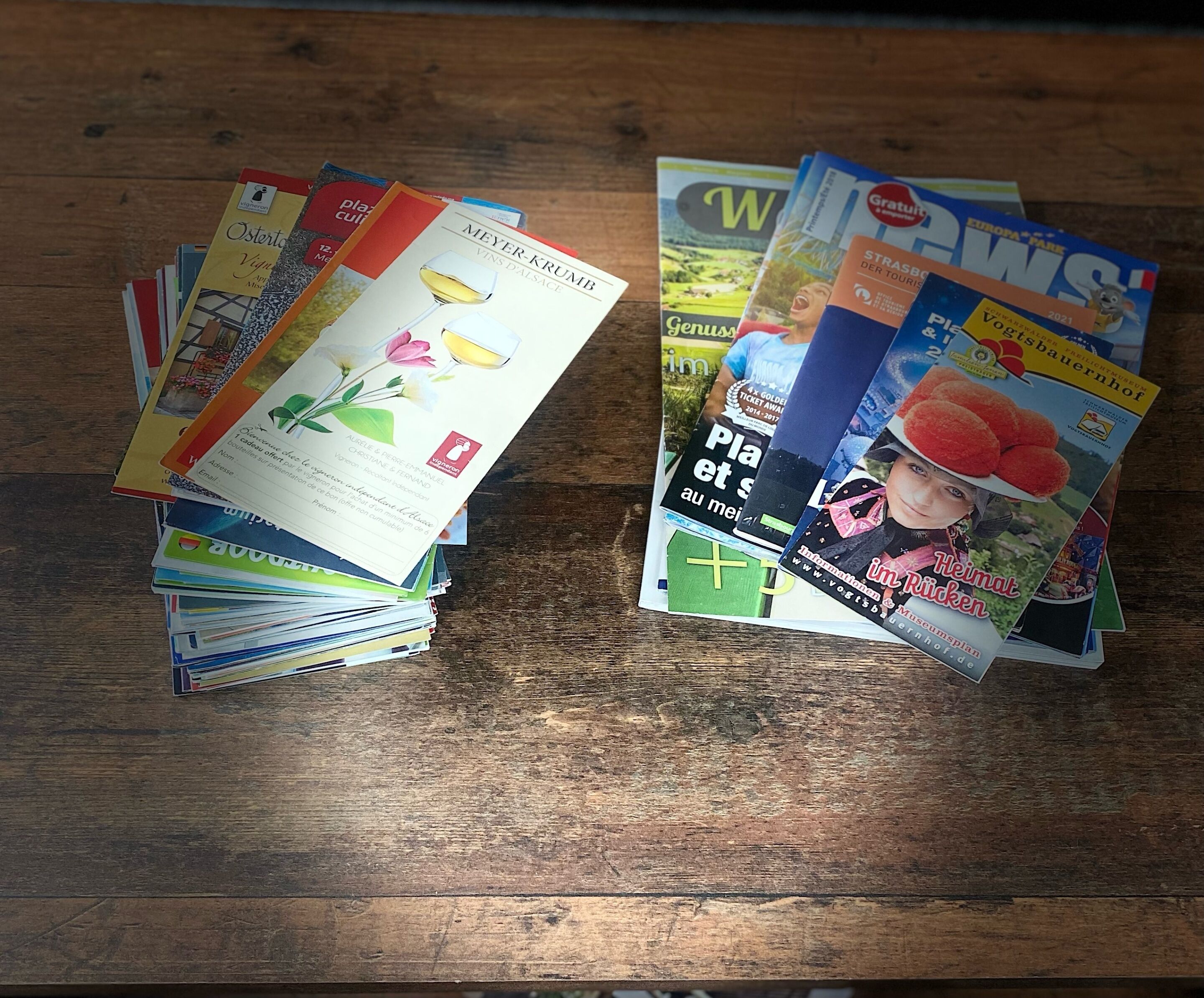Zeitschriften und Broschüren liegen auf einem Holztisch.