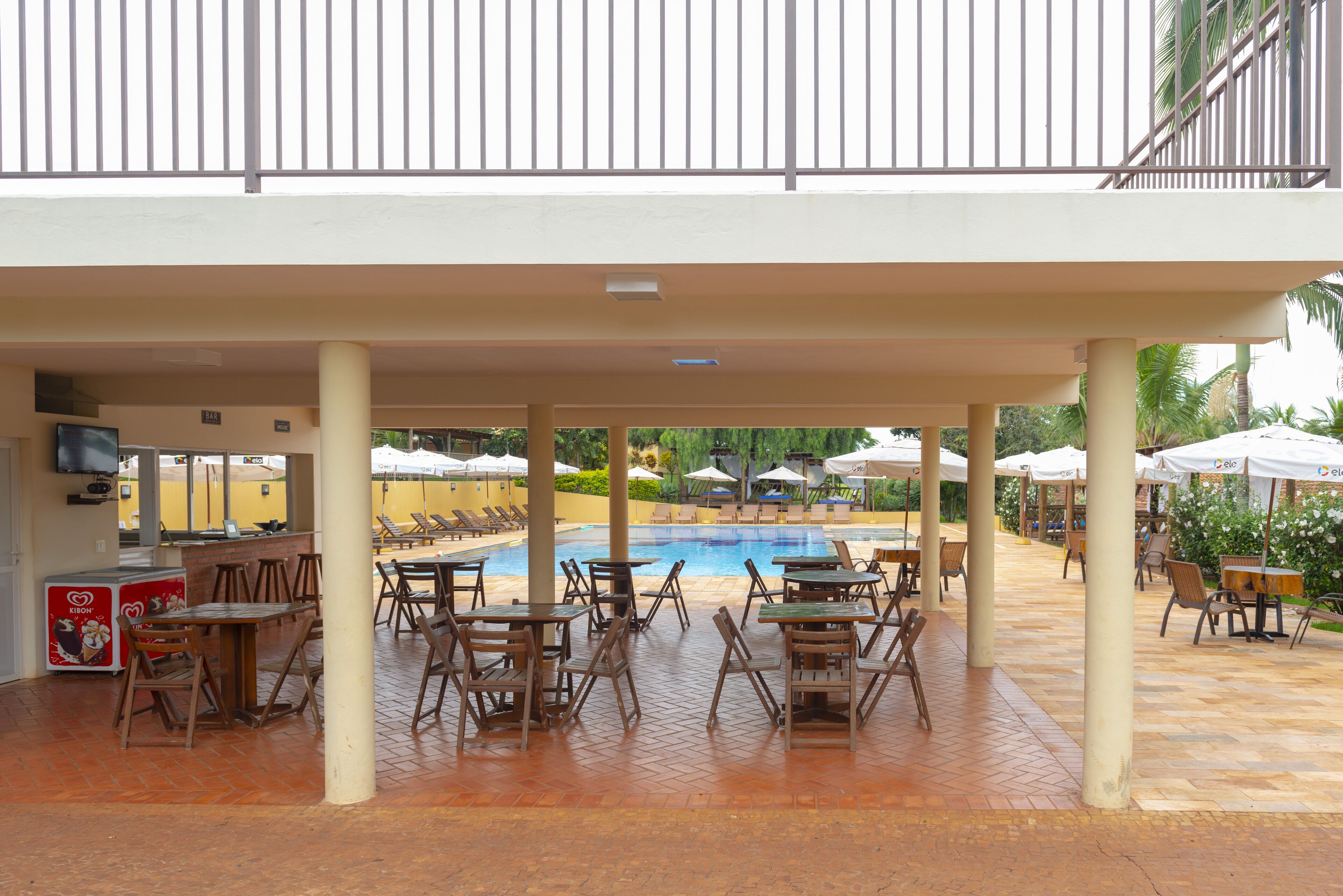 An outdoor pool area with multiple lounge chairs and tables, a pool, and umbrellas.