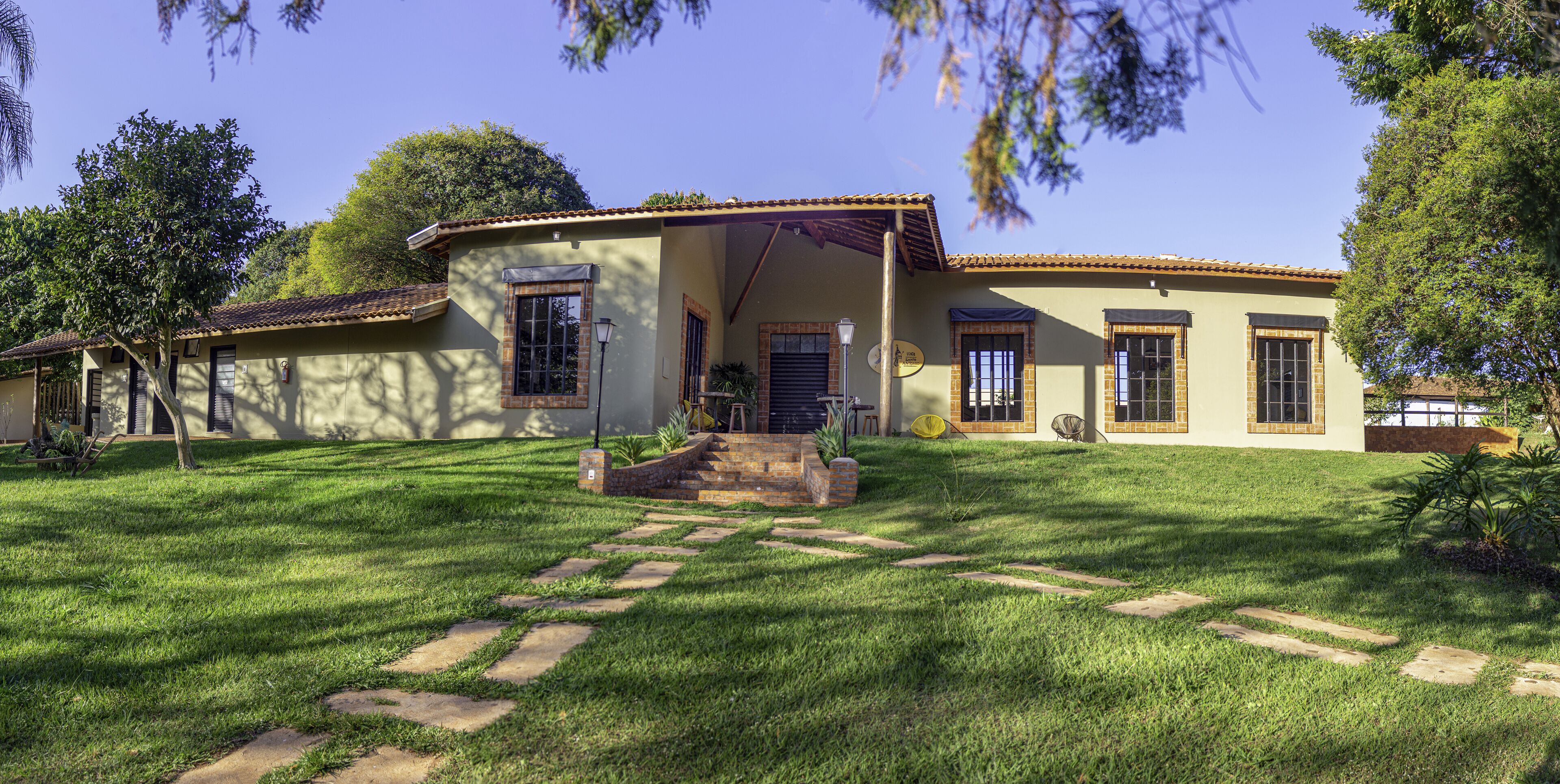 A two-story house with a patio, a stone pathway, and a lawn.