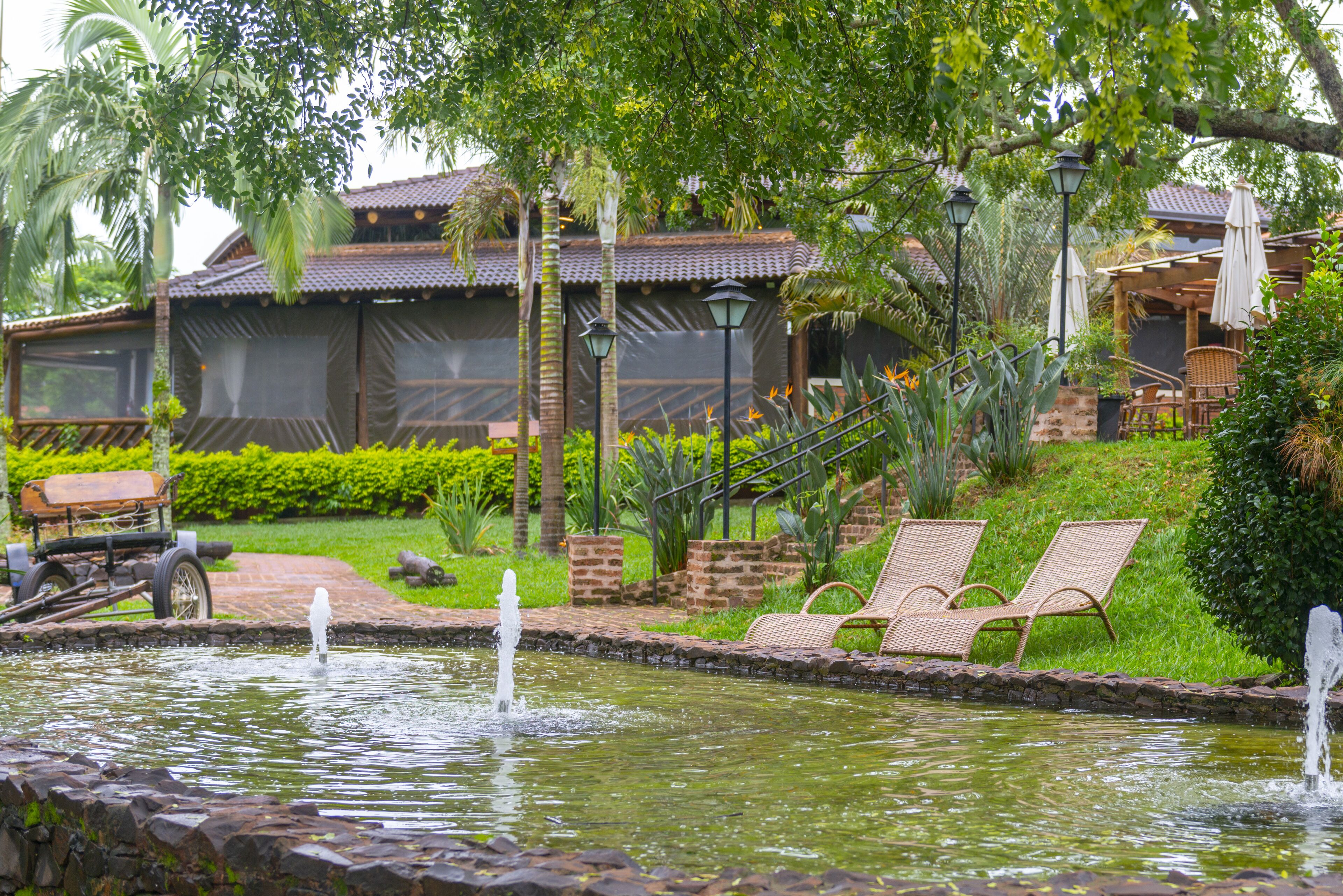 A serene garden with a pond, lounge chairs, and a traditional building with a tiled roof.