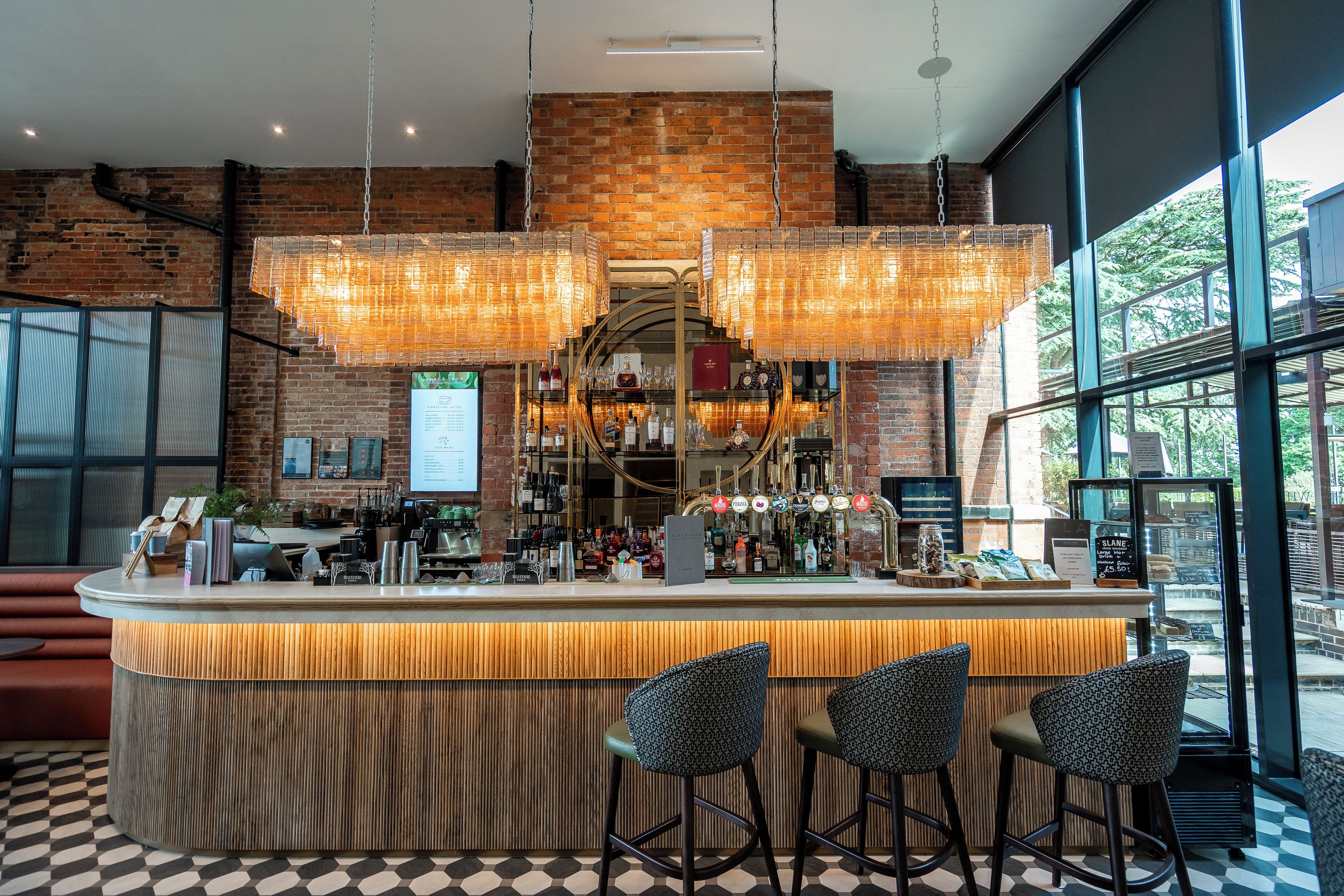 Un espace bar avec un mur en briques, des luminaires suspendus et un comptoir avec des tabourets.