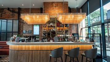 Un espace bar avec un mur en briques, des luminaires suspendus et un comptoir avec des tabourets.