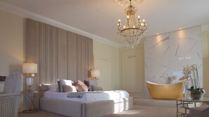A spacious bedroom with a large bed, a bathtub, and a chandelier. - Winstanley House (Leicester)